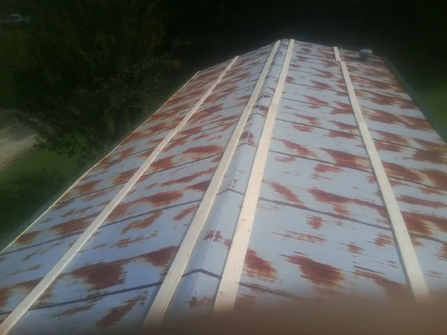 Rusted metal roof panels with new wood purlins before replacement — Storm Damage Roof Repair in Patricksburg by Roofing Brothers