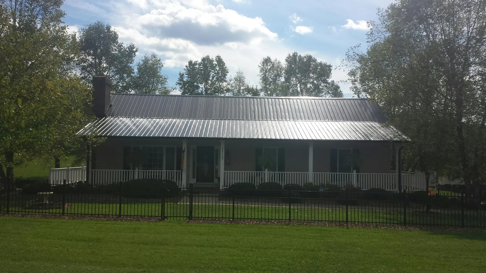 Gray metal roof on a brick ranch with a full width front porch — Gutter Guard Installation work by our crew in Patricksburg