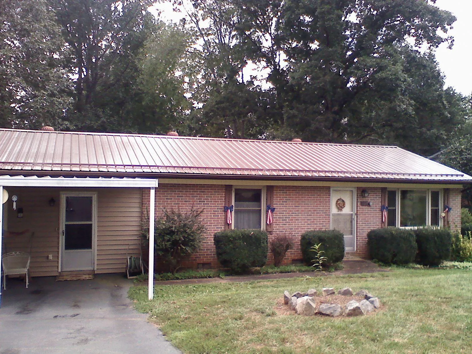 Bronze metal roof and carport on a brick ranch home — Roof Repair work by our crew in Patricksburg