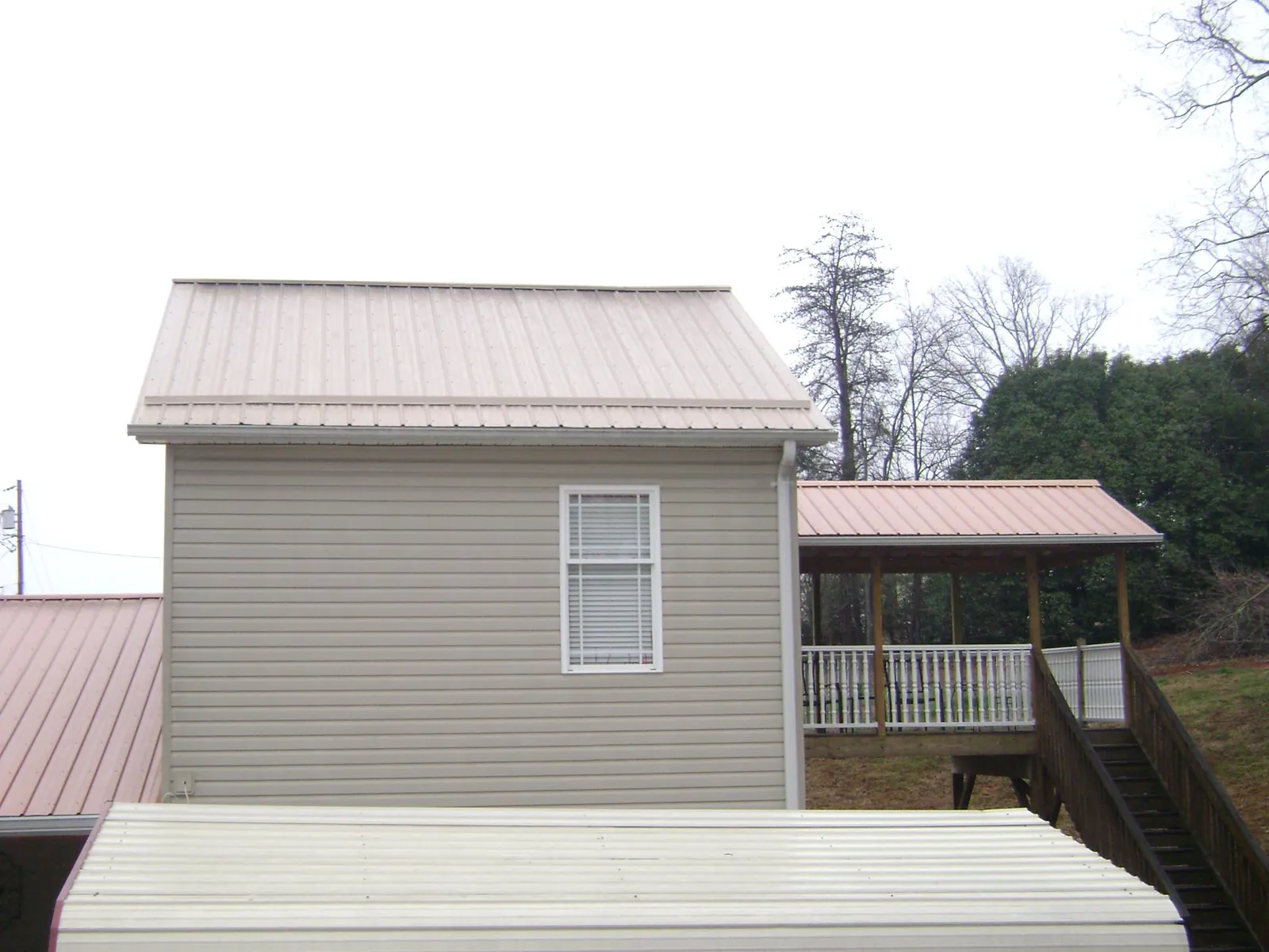 Tan metal roofs on a two story addition and attached porch, from a Roof Replacement job in Patricksburg
