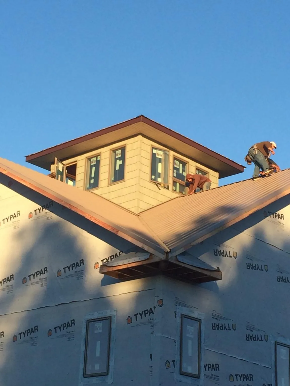 Roofers working around a rooftop cupola on a new metal roof at sunset — Roof Waterproofing in Patricksburg by Roofing Brothers